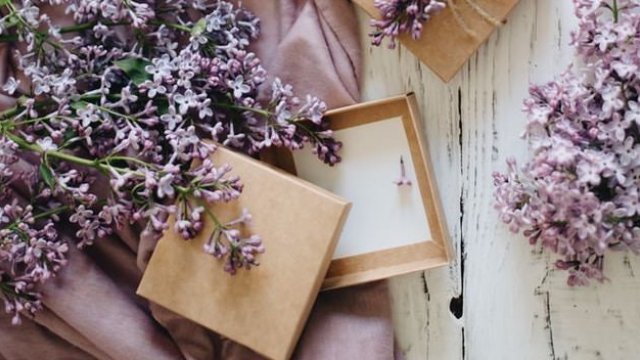 Lila Blumen und offene Geschenkboxen auf lila Tuch