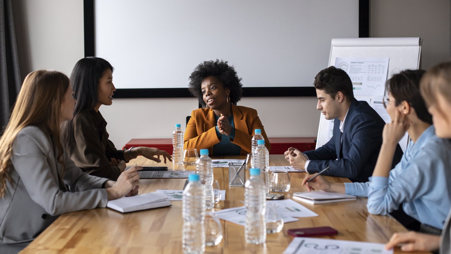 A group of people in a meeting room discussing accessible communication together at the table.
