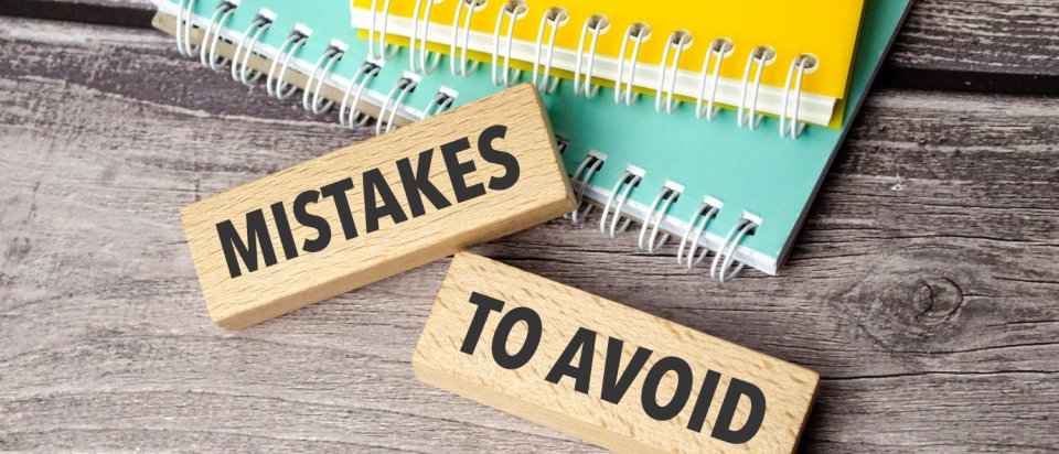 Mistakes to avoid on wooden blocks laying on a desk with note books