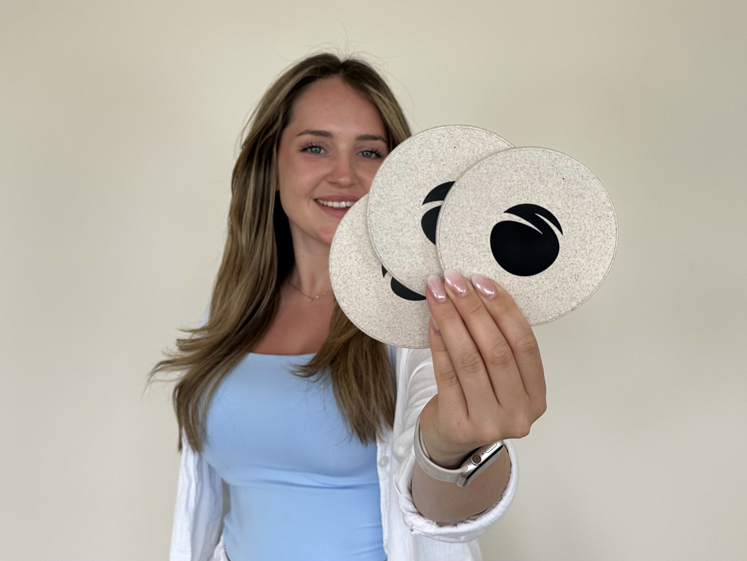 The author, Mia, holds a round, white desktop charging station made from recycled housing, a sustainable tech giveaway