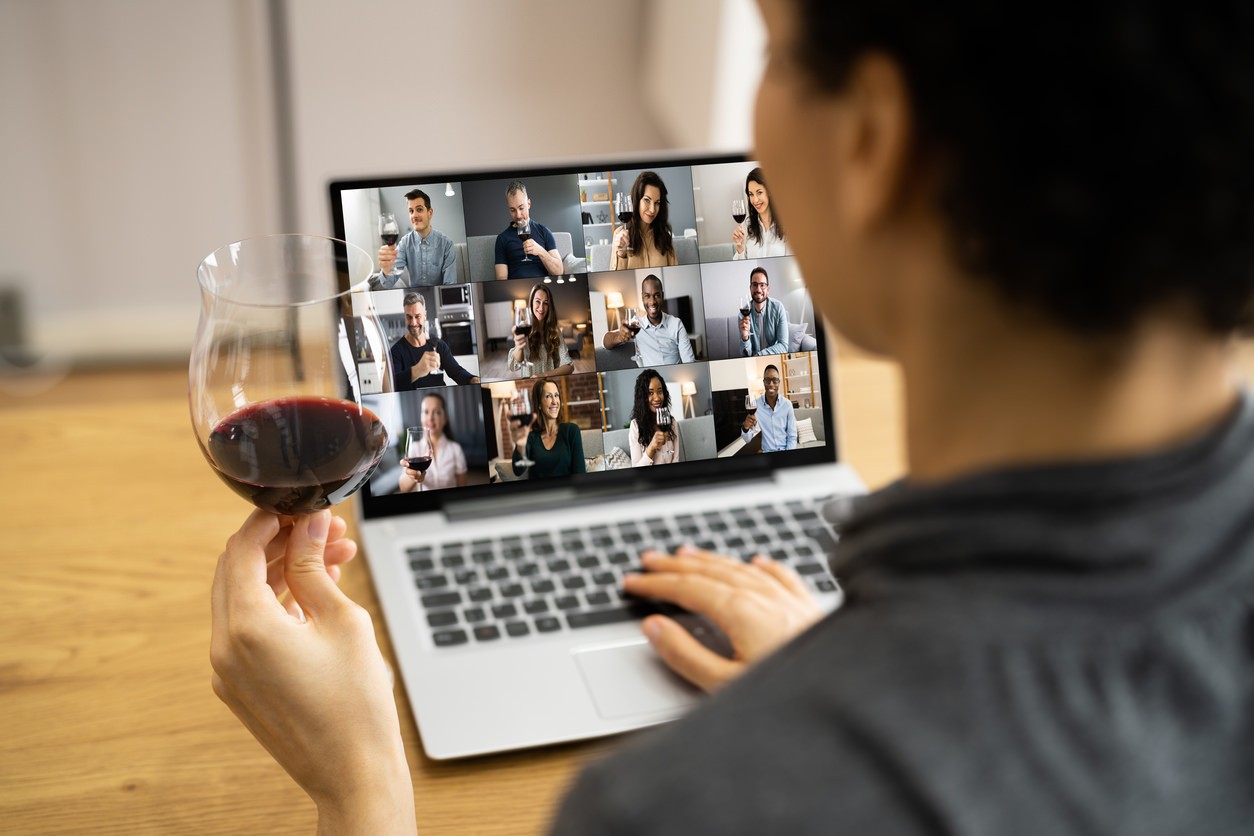 Person holding a glass of wine while having virtual wine tasting meeting