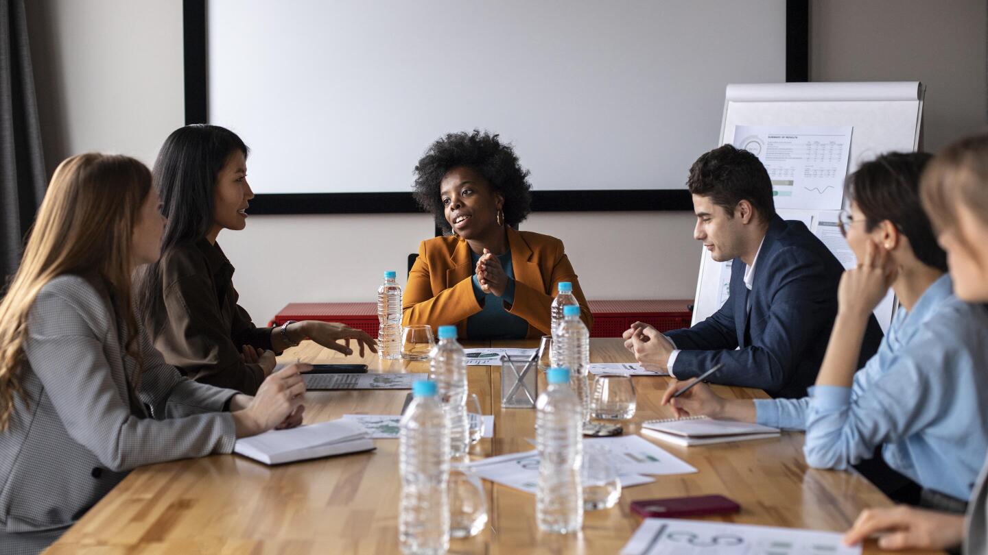 A group of people in a meeting room discussing accessible communication together at the table.
